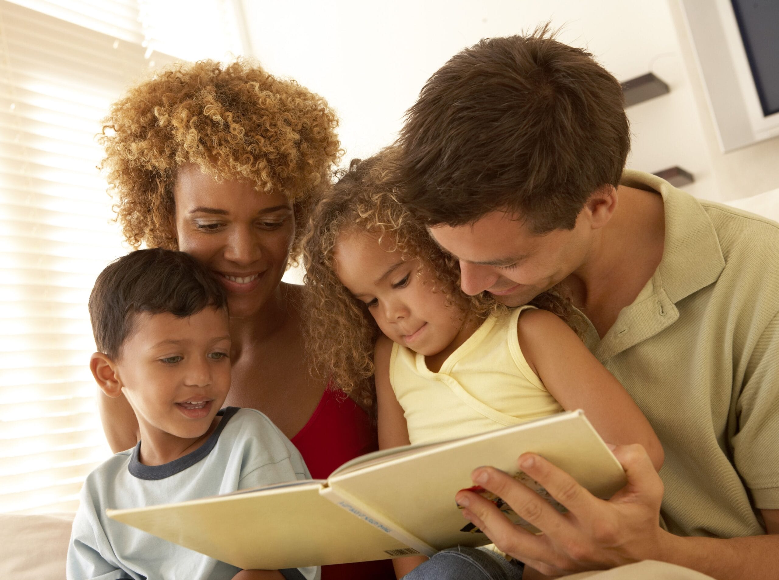 Family reading book on the couch together.